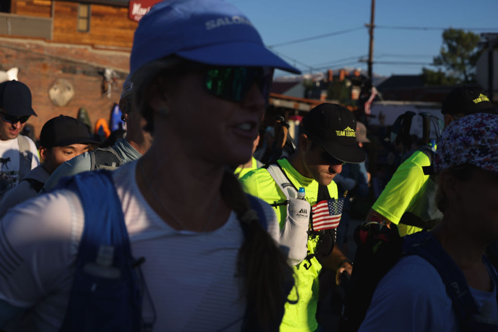 Veterans and supporters wearing Warriors’ Ascent gear participate in an endurance race, moving together through a mountain town during a long-distance event.